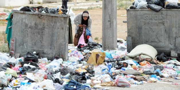 GO WITH STORY BY MARINE MESSINA - A woman inspects uncollected rubbish poured on the ground on May 27, 2014 in El Agba, north of the Tunisian capital, Tunis. Fed up with the dirt and the inefficiency of the authorities, volonteers and citizens have launched several initiatives to clear up their neighborhoods. AFP PHOTO / FETHI BELAID (Photo credit should read FETHI BELAID/AFP/Getty Images)