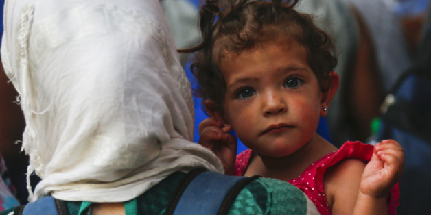 A traveller believed to be a migrant holds her child as she leaves a train coming from Austria at the railway station in Munich, Germany, August 31, 2015. Austrian authorities toughened controls along the country's eastern borders on Monday, stopping hundreds of refugees and arresting five traffickers in a clampdown that followed last week's gruesome discovery of 71 dead migrants in a truck. REUTERS/Michael Dalder