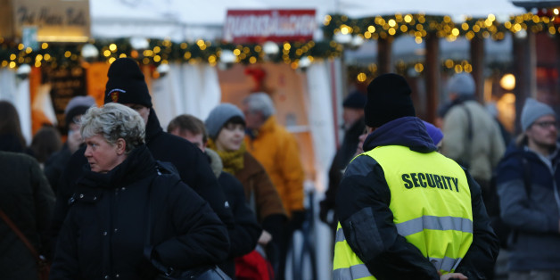 A security officer watches people visiting the Gendarmenmarkt Christmas market on the first day of its opening in Berlin, Germany, November 23, 2015. The security measures in public places were increased after recent deadly attacks in Paris. REUTERS/Hannibal Hanschke