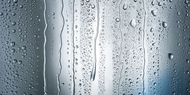 Heavy condensation forms droplets and streams of water running down a dark blue shadowy background