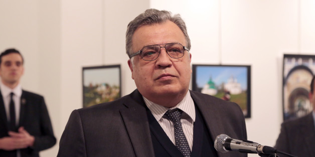 The Russian Ambassador to Turkey Andrei Karlov speaks a gallery in Ankara Monday Dec. 19, 2016. A gunman opened fire on Russia's ambassador to Turkey Karlov at a photo exhibition on Monday. The Russian foreign ministry spokeswoman said he was hospitalized with a gunshot wound. The gunman is seen at rear on the left. (AP Photo/Burhan Ozbilici)