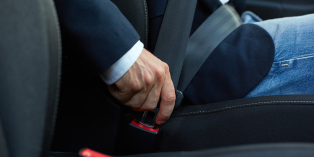 Driver sits in the car and fastens his seat belt