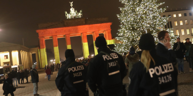 BERLIN, GERMANY - DECEMBER 20: The Brandenburg Gate stands illuminated in the colors of the German flag as police walk past the day after a truck drove into a crowded Christmas market in the city center on December 20, 2016 in Berlin, Germany. So far 12 people are confirmed dead and 45 injured. Authorities have confirmed they believe the incident was an attack and have arrested a Pakistani man who they believe was the driver of the truck and who had fled immediately after the attack. Among the dead are a Polish man who was found on the passenger seat of the truck. Police are investigating the possibility that the truck, which belongs to a Polish trucking company, was stolen yesterday morning. (Photo by Sean Gallup/Getty Images)
