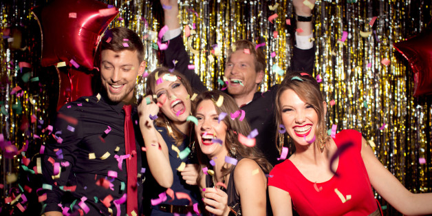 Young people wearing elegant clothes celebrating or having party in front of fringe curtain. They are dancing, smiling and having fun, confetti is in the air, dancing in night club.