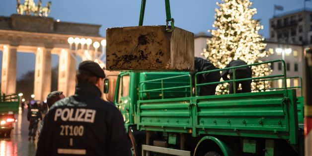 Policemen install a concrete barricade near the Brandenburg Gate in Berlin on December 22, 2016.
The Berlin Christmas market that was struck by a deadly truck rampage on December 19, 2016 reopened, as the grieving city sought a return to normal life and police hunted for the prime suspect in the attack. / AFP / CLEMENS BILAN (Photo credit should read CLEMENS BILAN/AFP/Getty Images)
