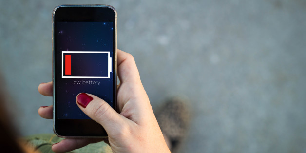 Top view of woman walking in the street using her mobile phone with low battery on screen with copyspace. All screen graphics are made up.