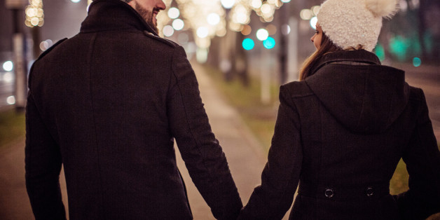 Young couple walking in downtown for Christmas . Wearing warm clothes, hats and scarves. Vienna, Austria. Smiling and talking.