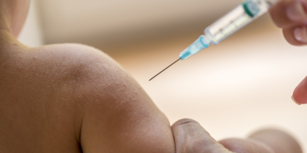 Doctor injecting a young child with a vaccination or antibiotic in a small disposable hypodermic syringe, close up of the kids arm and needle.