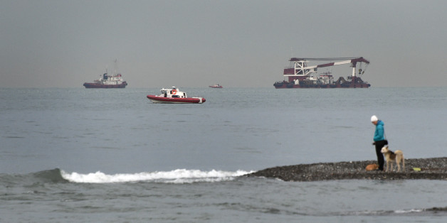 A woman walks with her dog on the shore of the Black Sea outside Sochi, on December 27, 2016, as rescue vessels search the area two days after a military plane carrying 92 people, including dozens of members of the Red Army Choir, crashed in the Black Sea.Russian divers were scouring the Black Sea on December 27, 2016 for more debris and bodies from a Syria-bound military plane after finding the first wreckage underwater, as officials dismissed terrorism as a cause of the crash that killed all 9