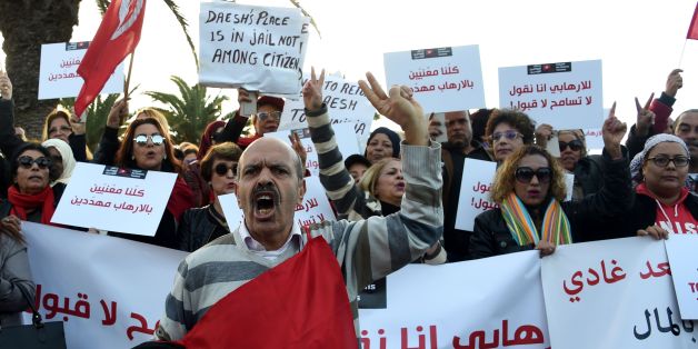 Tunisians shout slogans during a demonstration outside parliament against allowing Tunisians who joined the ranks of jihadist groups to return to the country, in the capital Tunis on December 24, 2016. The writing in Arabic reads: ''we are all under threat by terrorism''. / AFP / FETHI BELAID (Photo credit should read FETHI BELAID/AFP/Getty Images)
