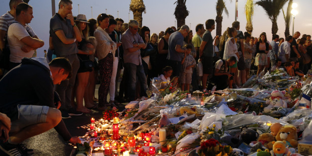 People gather around flowers and burning candles to pay tribute to victims of the truck attack along the Promenade des Anglais on Bastille Day that killed scores and injured as many in Nice, France, July 17, 2016. REUTERS/Pascal Rossignol