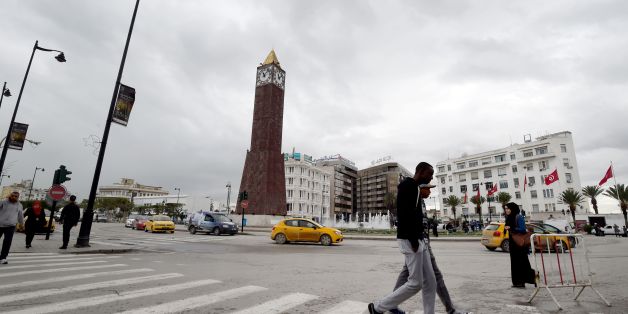 A photo taken on November 10, 2016 shows Tunisians walking past the Great Clock in the Habib Bourguiba avenue in the capital Tunis. A Tunisian man climbed the Great Clock of the Habib Bourguiba avenue of the capital, early in the morning, and was ready to jump into the void in protest against the election of Donald Trump as the President of the United States. / AFP / FETHI BELAID (Photo credit should read FETHI BELAID/AFP/Getty Images)