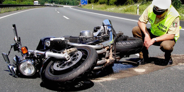Ein Polizist begutachtet das Motorrad eines tödlich verunglückten Fahrers auf der Autobahn 45 bei Siegen