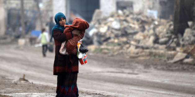 A woman carries a child as she walks near rubble of damaged buildings in al-Rai town, northern Aleppo countryside, Syria December 25, 2016. REUTERS/Khalil Ashawi
