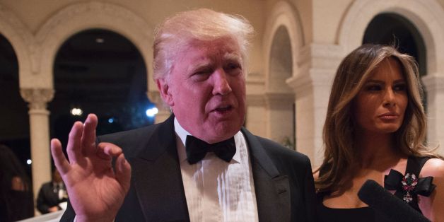 US President-elect Donald Trump answers questions from reporters accompanied by his wife Melania for a New Year's Eve party December 31, 2016 at Mar-a-Lago in Palm Beach, Florida. / AFP / DON EMMERT (Photo credit should read DON EMMERT/AFP/Getty Images)