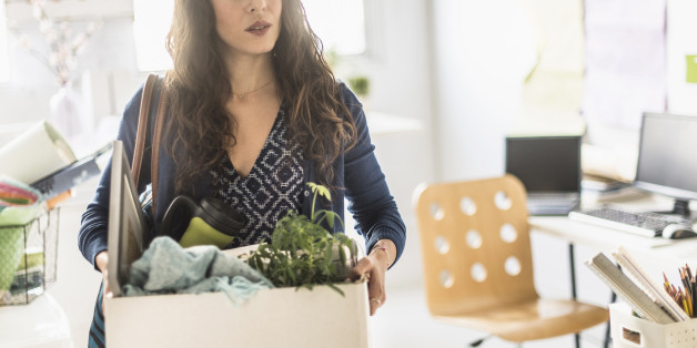 Hispanic businesswoman carrying cardboard box in office