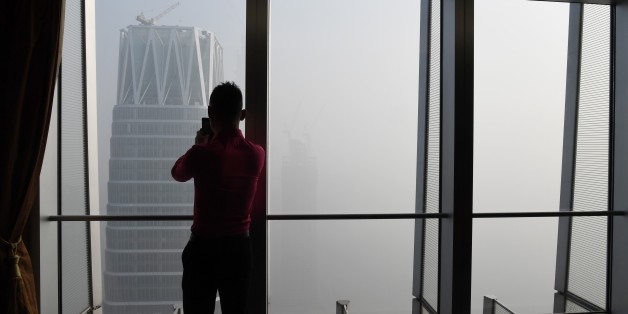 A man takes photos of buildings on a polluted day in Beijing on January 1, 2017. China's capital city started the year under a heavy blanket of grey smog, with a concentration of toxic particles 20 times higher than the maximal level recommended by the World Health Organization, as a new pollution cloud was - again - striking the country. / AFP / GREG BAKER (Photo credit should read GREG BAKER/AFP/Getty Images)