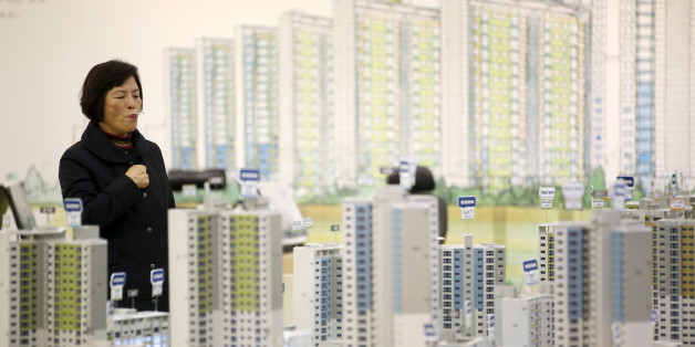 A visitor looks at a miniature model of an apartment complex which is currently under construction at its showroom in Seoul March 18, 2015. While activity is soaring, with the number of transactions at a 7-year high, housing prices are rising at a glacial pace as heavy household debt and a fast-ageing population keep a lid on price growth. To match story SOUTHKOREA-ECONOMY/HOUSING Picture taken on March 18. REUTERS/Kim Hong-Ji