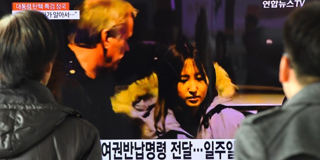 People watch a screen showing a news report on the arrest of Chung Yoo-Ra (C), the 20-year-old daughter of the woman dubbed South Korea's 'Rasputin', at a railway station in Seoul on January 3, 2017.
The daughter of Choi Soon-Sil, the woman at the centre of a corruption scandal that led to the impeachment of South Korea's president, has been arrested in Denmark after months in hiding, Danish police said. / AFP / JUNG Yeon-Je (Photo credit should read JUNG YEON-JE/AFP/Getty Images)