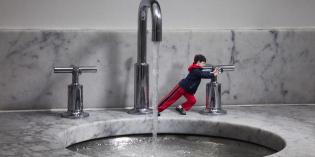 Miniature boy turning off water tap