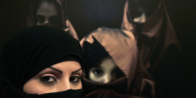 Saudi photographer Muneera Al Romaih poses in front of one of her photographs during the opening of a gallery by a group of Saudi women photographers in Amman April 8, 2009. REUTERS/Muhammad Hamed (JORDAN SOCIETY)