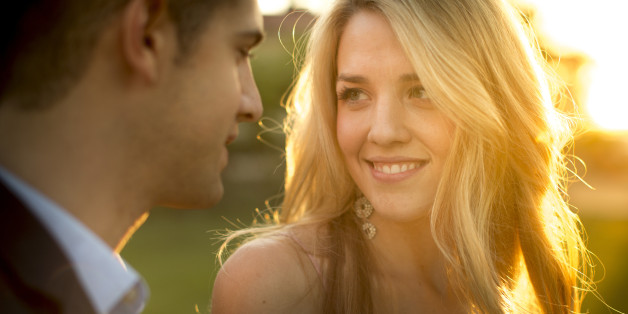 A pretty young girl stares at the eyes of a smart young man stands close to her.