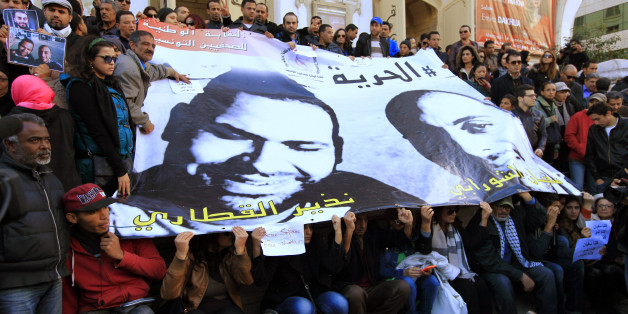 People pose around a poster of journalists Nadhir Ktari (L, in poster) and Sofiane Chourabi, who went missing in Libya in September, during a demonstration over their disappearance, in Tunis January 9, 2015. REUTERS/Anis Mili (TUNISIA - Tags: CIVIL UNREST POLITICS CRIME LAW MEDIA)