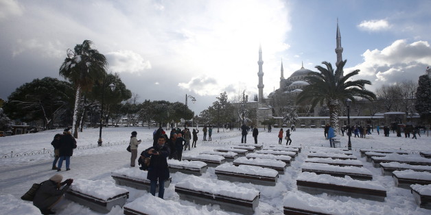 Tourists take a photo on the snow-covered Sultanahmet Square in the historic old town of Istanbul, Turkey, December 31, 2015. REUTERS/Osman Orsal