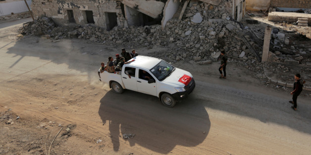 Free Syrian Army fighters ride on a pick-up truck decorated with a Turkish flag past damaged buildings in the northern Syrian rebel-held town of al-Rai, in Aleppo Governorate, Syria, October 5, 2016. REUTERS/Khalil Ashawi