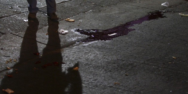The shadow of a police officer is cast near a puddle of blood at a crime scene outside a nightclub in an upscale neighborhood of Guadalajara February 12, 2011. A group of hitmen showed up outside the club, started shooting and threw a grenade inside the building killing at least seven people and injuring another 30, according to local media. Cartel hitmen are murdering rivals and terrifying residents across Mexico's second city Guadalajara as it prepares to host the Pan American Games in a deepening of the country's drugs war. REUTERS/Alejandro Acosta (MEXICO - Tags: CRIME LAW CIVIL UNREST)