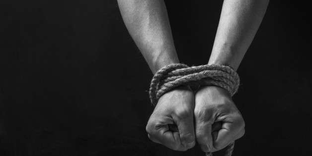 Hands tied with rope on a black background.