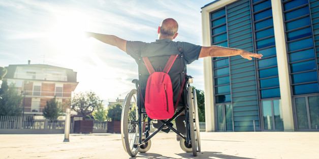 Invalid man sitting on a wheel chair and enjoying a walk outdoors