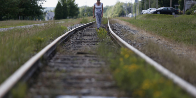 A woman walks on the railway close to the train wreck in Lac-Megantic July 13, 2013. The crude oil freight train that derailed and blew up in the small town of Lac-Megantic early on Saturday morning was traveling far too fast when it went off the rails, investigators told reporters on Tuesday. REUTERS/Mathieu Belanger (CANADA - Tags: DISASTER TRANSPORT)