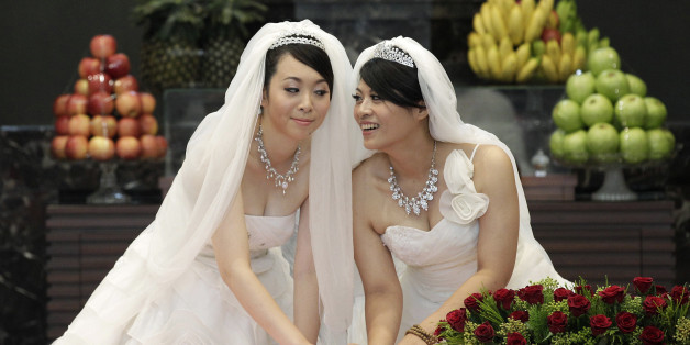 You Ya-ting (L) and Huang Mei-yu cast their stamps during their symbolic same-sex Buddhist wedding ceremony at a temple in Taoyuan county, northern Taiwan, August 11, 2012. The 30-year-old lesbian couple tied the knot after dating for seven years on Saturday in Taiwan's first same-sex Buddhist wedding. They hope this wedding will help make Taiwan the first place in Asia to legalise same-sex marriage. REUTERS/Pichi Chuang (TAIWAN - Tags: SOCIETY TPX IMAGES OF THE DAY)