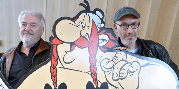 French cartoonist Didier Conrad (L), and the coauthor of the popular comic book Asterix with French cartoonist and author Albert Uderzo (unseen) writer and designer Jean-Yves Ferri pose beside a cardboard cut-out of Asterix and Obelix characters during a press conference in Paris on October 12, 2015 for the release of the new Asterix album 'Le Papyrus de Cesar' (Caesar's Papyrus). The 36th book in the Asterix series 'Le Papyrus de Cesar' (entitled in English : Asterix and the Missing Scroll), wi