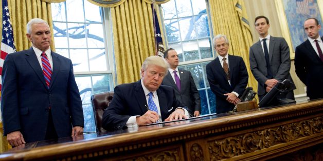 US President Donald Trump signs an executive order in the Oval Office of the White House in Washington, DC, January 23, 2017.Trump on Monday signed three orders on withdrawing the US from the Trans-Pacific Partnership trade deal, freezing the hiring of federal workers and hitting foreign NGOs that help with abortion. / AFP / SAUL LOEB (Photo credit should read SAUL LOEB/AFP/Getty Images)