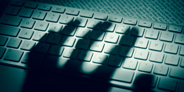 A menacing hand'ÂÂs shadow on a computer keyboard in front of printed computer data. Dramatic light, high contrast.