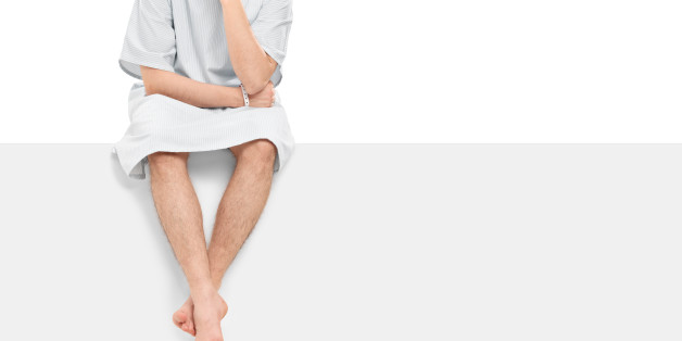 Worried male patient sitting on a blank panel isolated on white background