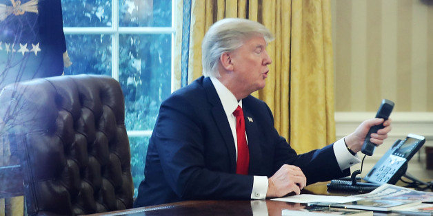WASHINGTON, DC - JANUARY 29: President Donald Trump is seen through a window making a phone call to King of Saudi Arabia, Salman bin Abd al-Aziz Al Saud, in the Oval Office of the White House, January 29, 2017 in Washington, DC. On Sunday, President Trump is making several phone calls with world leaders from the Oval Office. (Photo by Mark Wilson/Getty Images)