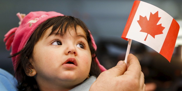 A young Syrian refugee looks up as her father holds her and a Canadian flag at the as they arrive at Pearson Toronto International Airport in Mississauga, Ontario, December 18, 2015. REUTERS/Mark Blinch TPX IMAGES OF THE DAY