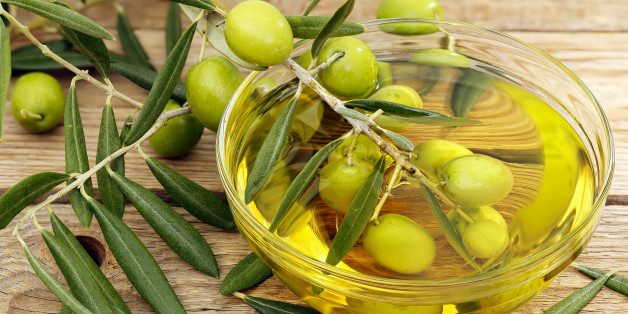 olive tree branch dipped in bowl of olive oil
