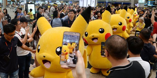 Fans gather to watch the Pokemon Go virtual reality game mascot Pikachu parade during a promotional event at the Changi International airport terminal in Singapore on November 18, 2016. Hundreds of Pokemon fans gathered at Changi Airport's Terminal 3 on November 18 to watch the Pikachu parade and Gingerbread House display which are part of the airport's year-end events. / AFP / Roslan RAHMAN (Photo credit should read ROSLAN RAHMAN/AFP/Getty Images)
