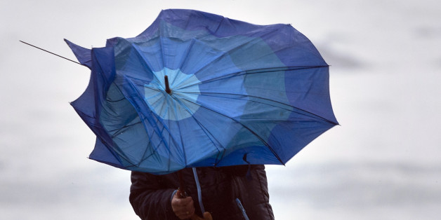 A man battles with his broken umbrella in heavy wind during stormy weather close to the town of Baiona, northwestern Spain, on February 3, 2017. / AFP / MIGUEL RIOPA (Photo credit should read MIGUEL RIOPA/AFP/Getty Images)