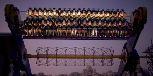 SHENZHEN, CHINA - SEPTEMBER 29: Chinese tourists ride a carnival ride at dusk at Happy Valley Theme park on September 29, 2008 in central Shenzhen, China. The park has various attractions such as roller coasters, water rides and Walt Disney style live shows for children. Chinese people love theme parks and new ones are opening constantly. It's estimated that there's about 2400 theme parks in the country. Many of the most popular parks are located around Shenzhen and over the border in Hong Kong. (Photo by Per-Anders Pettersson/Getty Images)