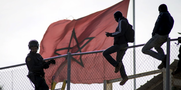African migrants sit on top of a border fence during an attempt to cross into Spanish territories, between Morocco and Spain's north African enclave of Melilla, November 21, 2015. REUTERS/Jesus Blasco de Avellaneda TPX IMAGES OF THE DAY