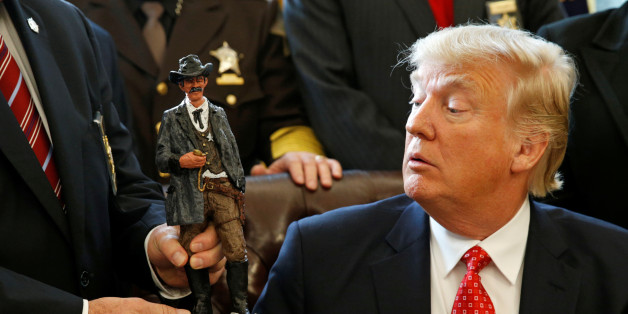 U.S. President Donald Trump receives a figurine of a sheriff during a meeting with county sheriffs at the White House in Washington, U.S. February 7, 2017. REUTERS/Kevin Lamarque TPX IMAGES OF THE DAY