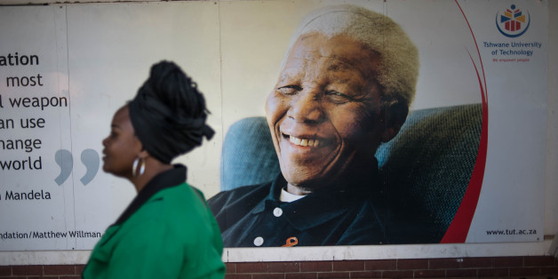 A South African woman walks in front of a poster of the late president Nelson Mandela as she joins a march towards the Union Buildings in Pretoria on August 9, 2016 during a celebration for Womens Day, an event marking the 60th anniversary of the 1956 women's march against the discriminatory pass laws, which restricted the movement of black people in the country. / AFP / MUJAHID SAFODIEN (Photo credit should read MUJAHID SAFODIEN/AFP/Getty Images)