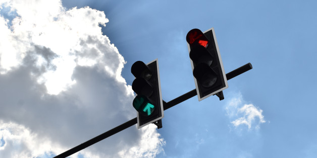 Ant view the traffic light turns green and red on background with a bright sky.