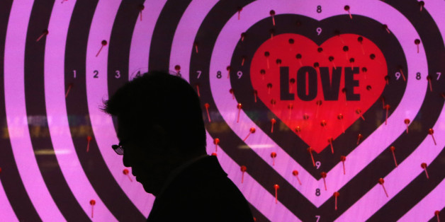 A man using his mobile phone walks past a shop window with signs advertising the upcoming Valentine's Day, at a luxury store in Tokyo January 30, 2014. Japan's core consumer prices rose 1.3 percent in December from a year earlier, the fastest pace in more than five years, adding to evidence the economy is making steady progress towards ending 15 years of grinding deflation. Picture taken January 30, 2014. REUTERS/Yuya Shino (JAPAN - Tags: BUSINESS)