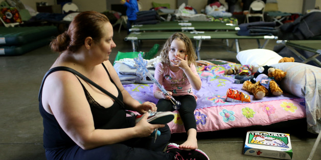 Jennifer Moss (L), of Marysville, ties her daughter Kaylin's shoes at the Salvation Army relief center at the Placer County Fair Grounds in Roseville, California, after an evacuation was ordered for communities downstream from the Lake Oroville Dam, in Oroville, California, U.S. February 14, 2017. REUTERS/Beck Diefenbach